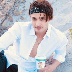 Asim Riaz in white shirt drinking coffee with a hairband on his forehead